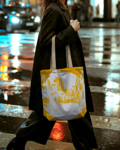 Person holding a yellow and white tote bag on a wet street at night.