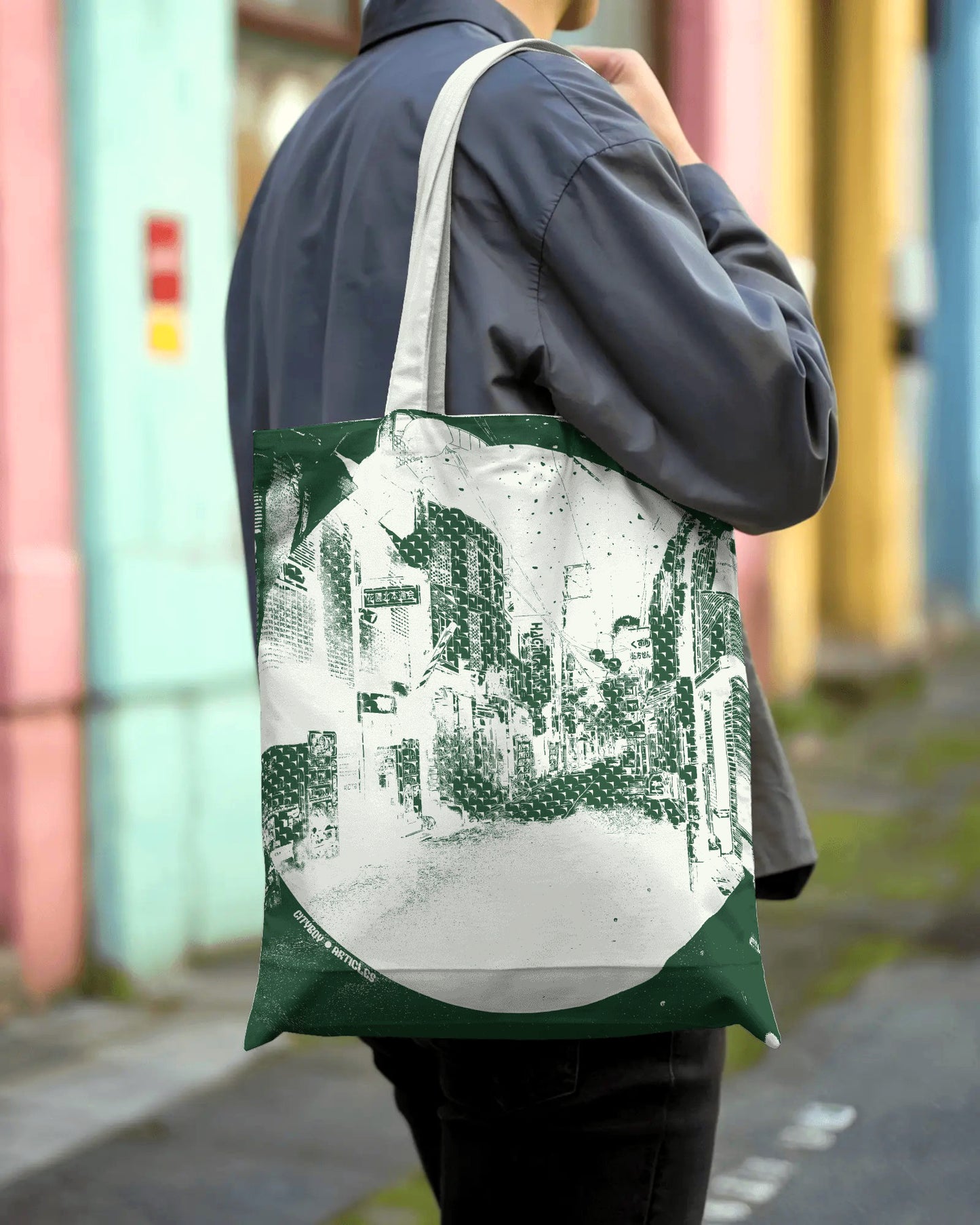 Person holding a tote bag with a cityscape design against a colorful building background
